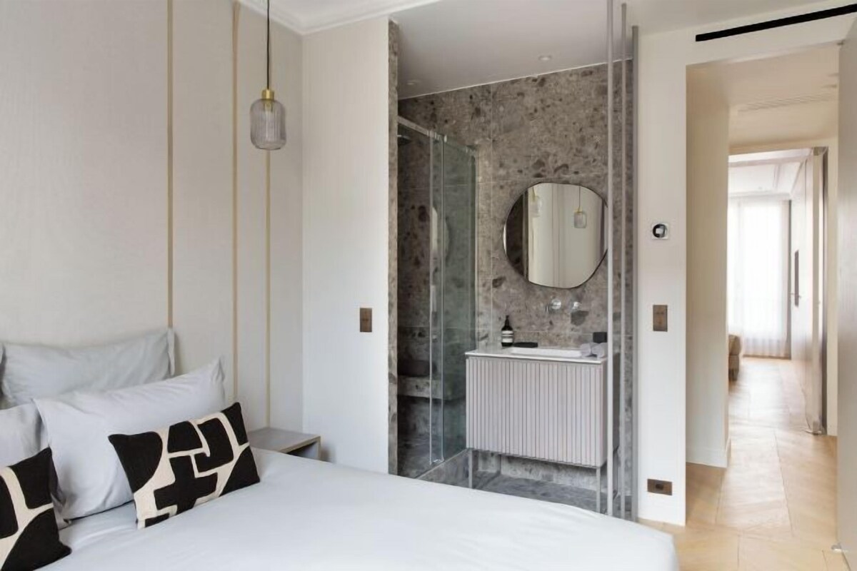 A modern bedroom with a large bed, a glass shower enclosure, and a white radiator.