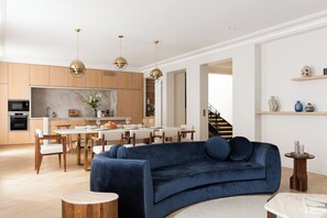 A modern living room with a blue sofa, wooden dining table, and pendant lights. - HIGHSTAY - Appartements de luxe - Arc de Triomphe (Paris)