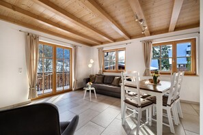 A room with a wooden ceiling, large windows, a sofa, a dining table with chairs, and a small side table with a vase. - Apartment 'Leibgeding' with Mountain View, Shared Terrace and Wi-Fi (Alpirsbach)
