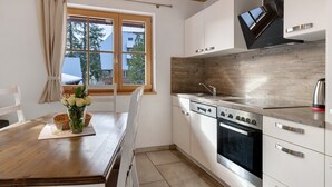 Una cocina moderna con armarios blancos, un horno de acero inoxidable y una ventana con vistas a edificios.