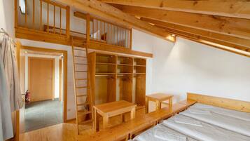 Een houten interieur met een slaapkamer op een entresol, een houten bank en een houten tafel.