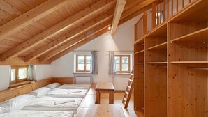 Una habitación con vigas de madera, literas, una mesa y una escalera.