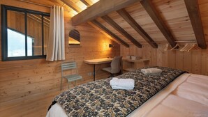 Quarto de cabana de madeira com cama, escrivaninha e cadeira.