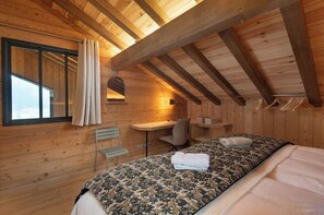 Habitación de cabaña de madera con una cama, un escritorio y una silla.