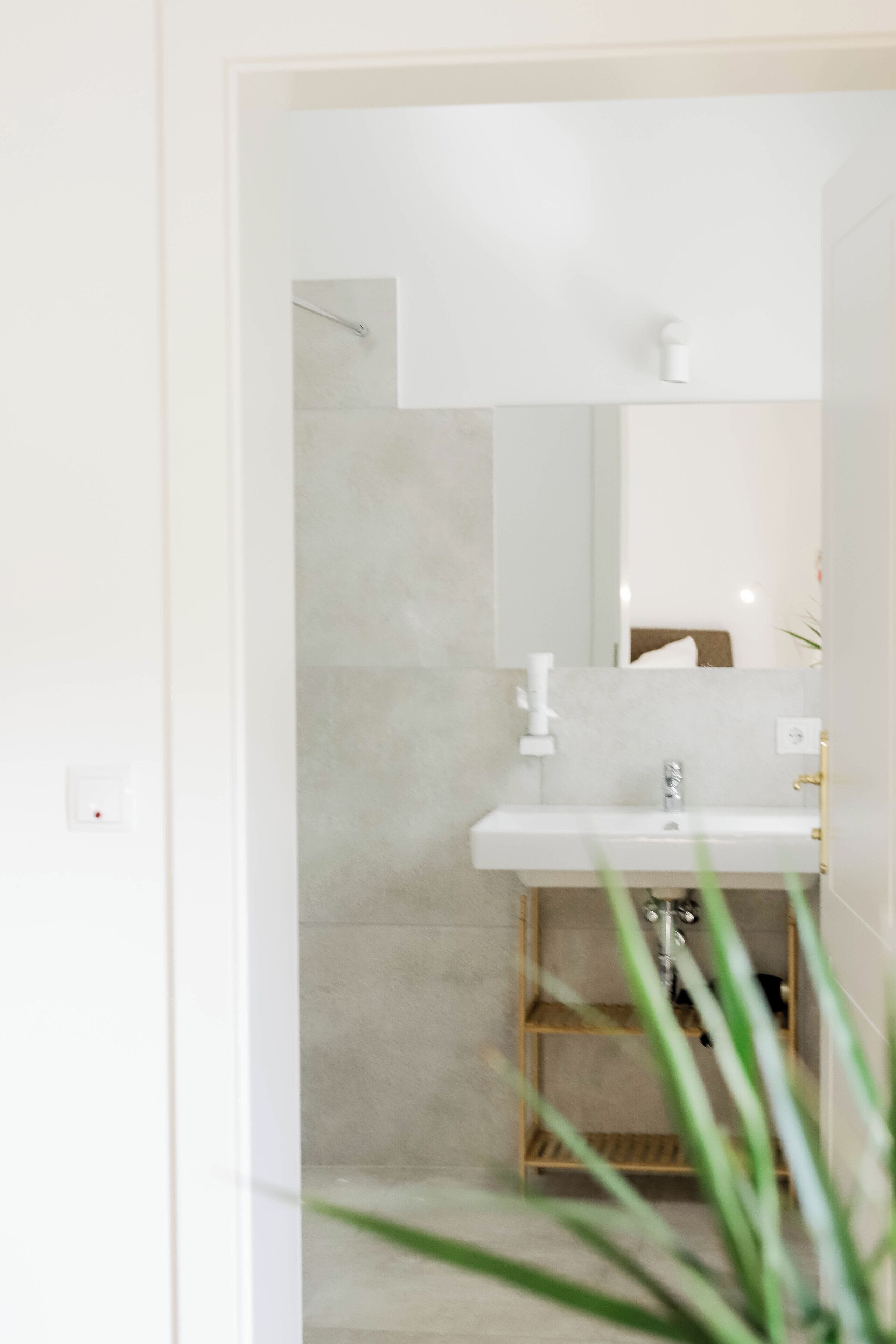 A modern bathroom with a white sink, a mirror, and a shower area.
