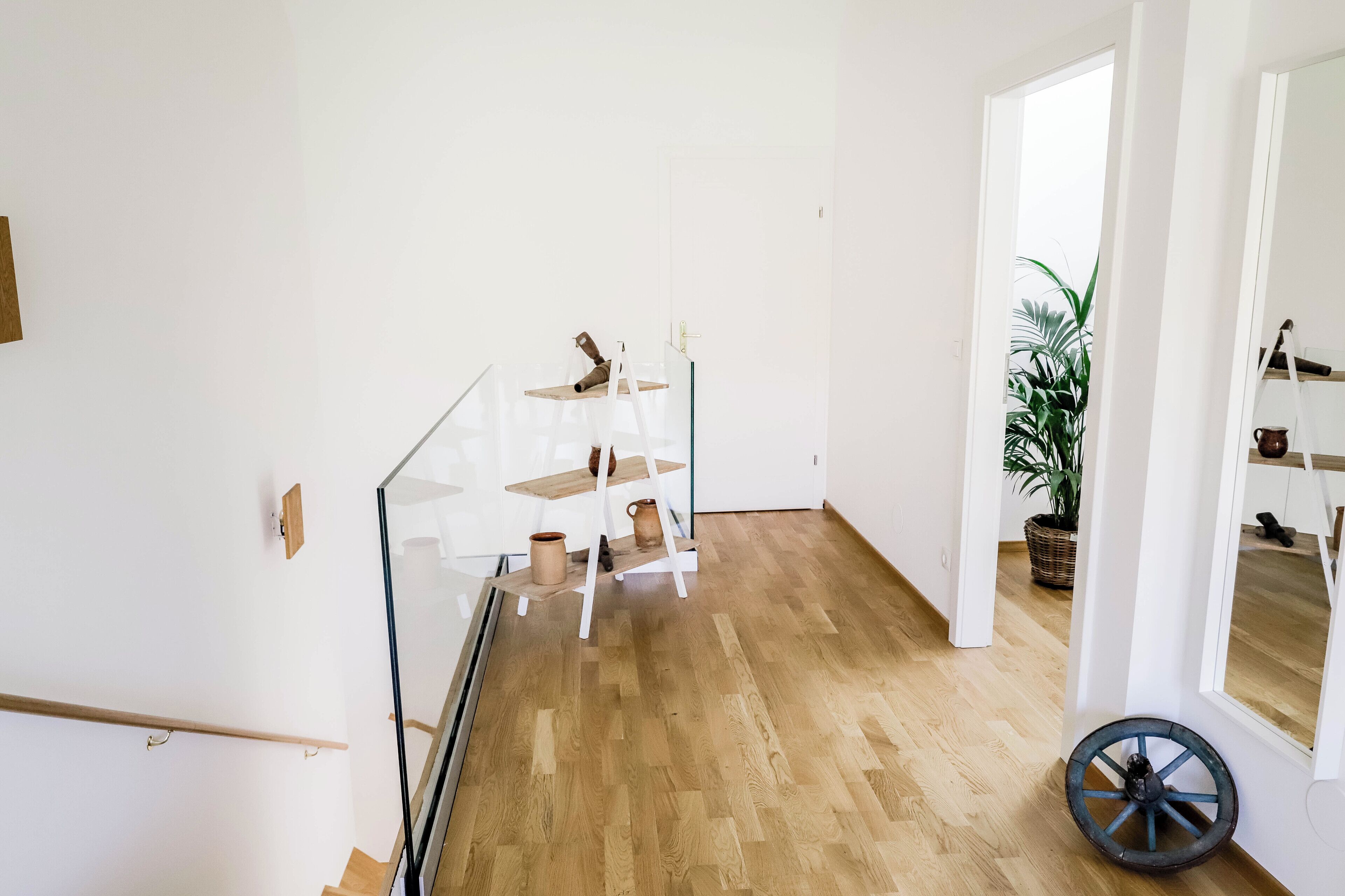 Un intérieur moderne avec un escalier, un plancher en bois et une rambarde en verre.