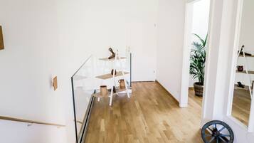 Un intérieur moderne avec un escalier, un plancher en bois et une rambarde en verre.