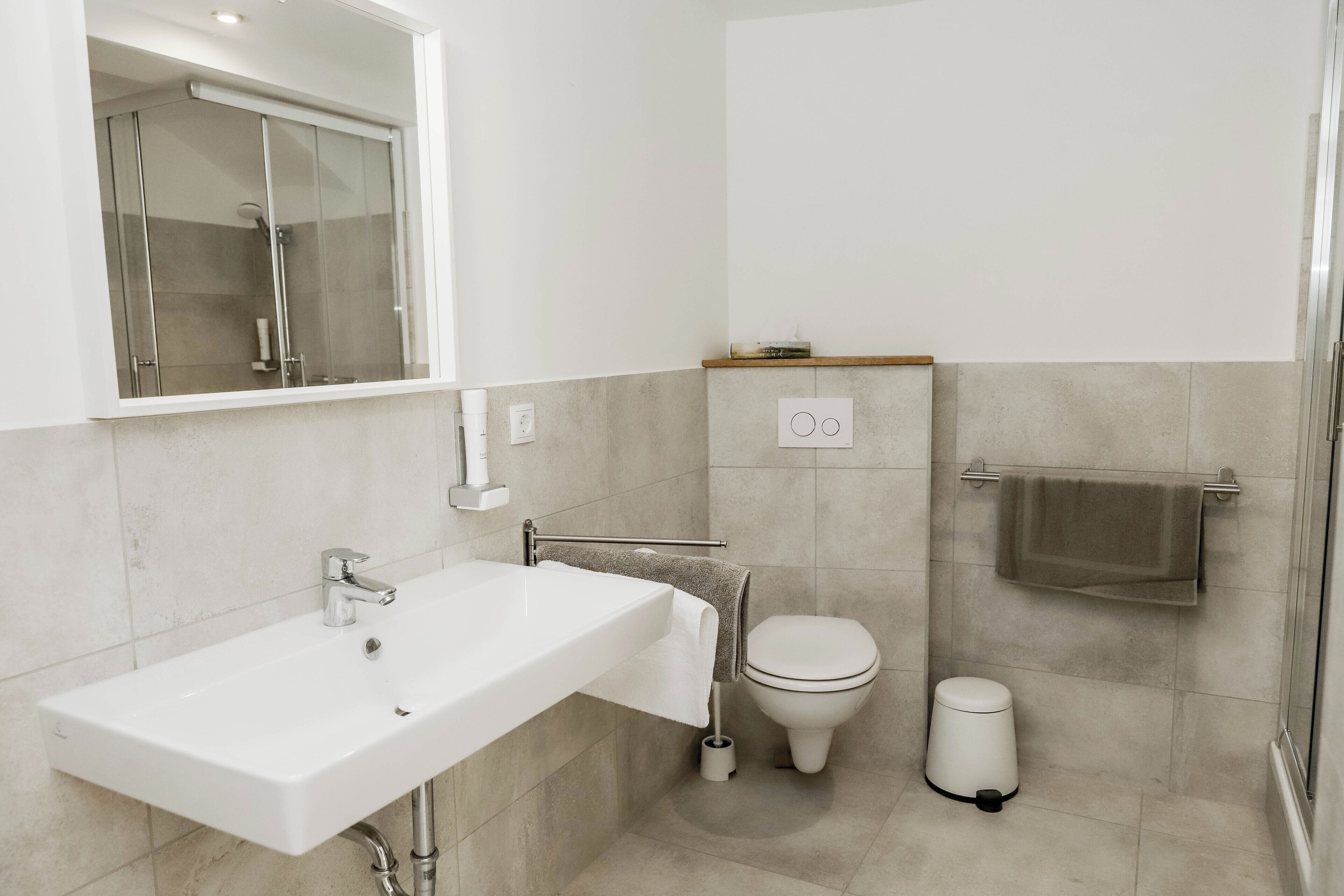 Un bagno moderno con un lavandino bianco, un water e una cabina doccia in vetro.