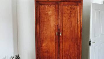 A wooden wardrobe with two doors and two drawers, placed in a room with a wooden floor and white walls.