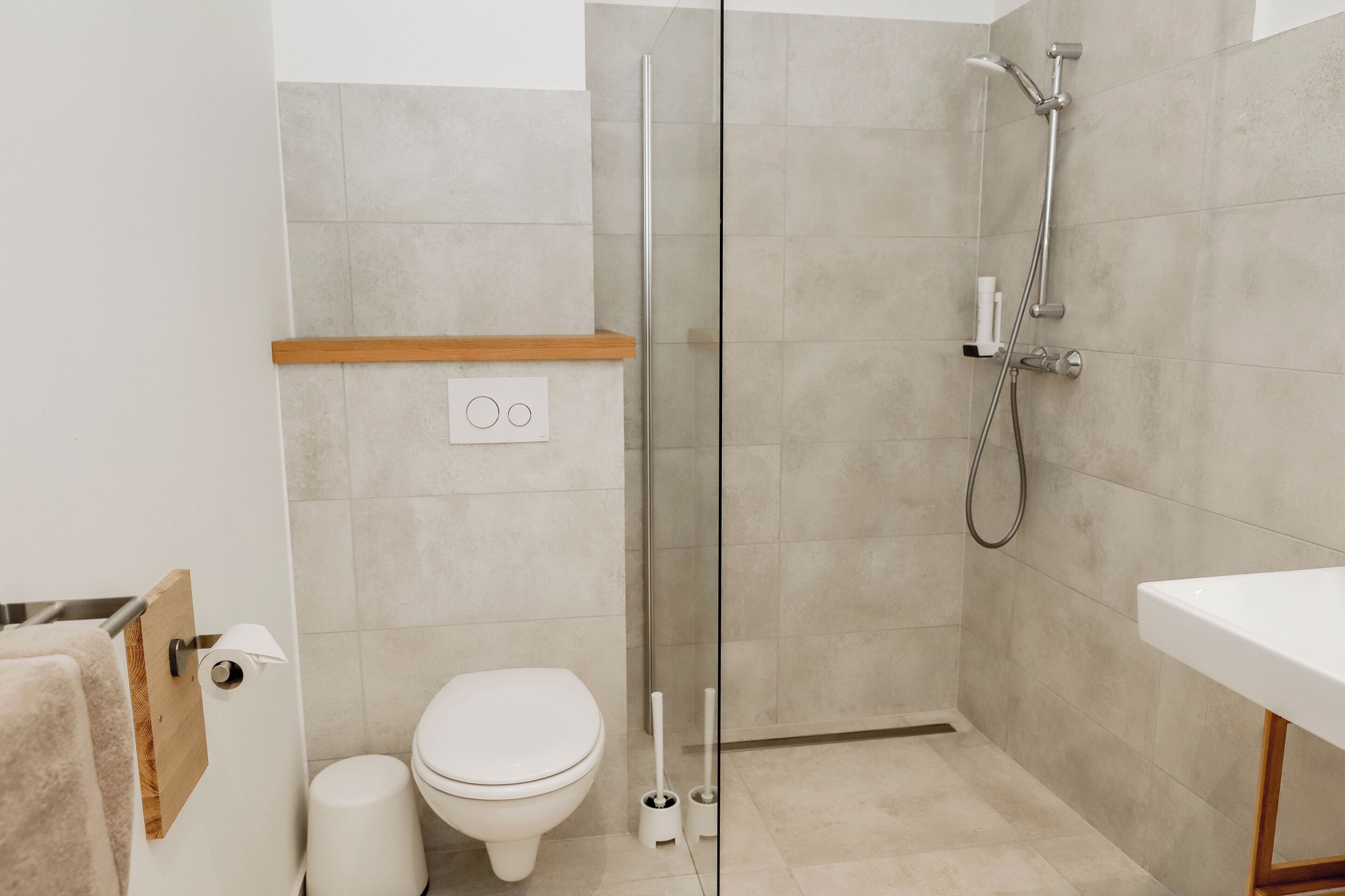 A modern bathroom with a toilet, a shower with a glass door, and a sink.