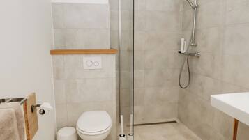 A modern bathroom with a toilet, a shower with a glass door, and a sink.