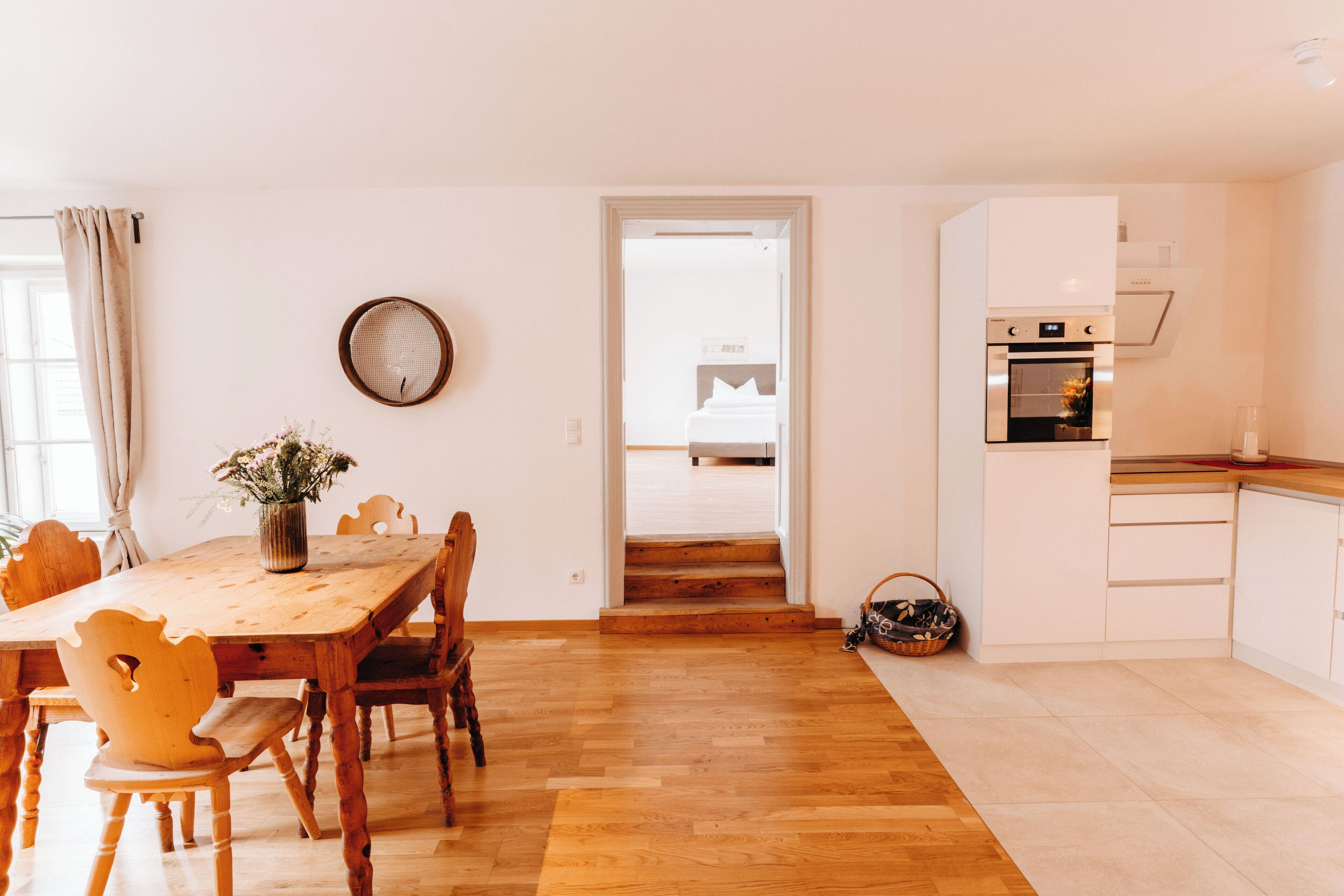 A modern kitchen with white cabinets and a wooden dining table.