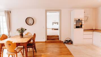 A modern kitchen with white cabinets and a wooden dining table.