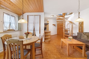 Un interior de madera con una mesa de comedor, sillas, un sofá y una escalera de caracol.