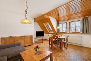 Una sala acogedora con sofá, mesa de comedor de madera y televisor.