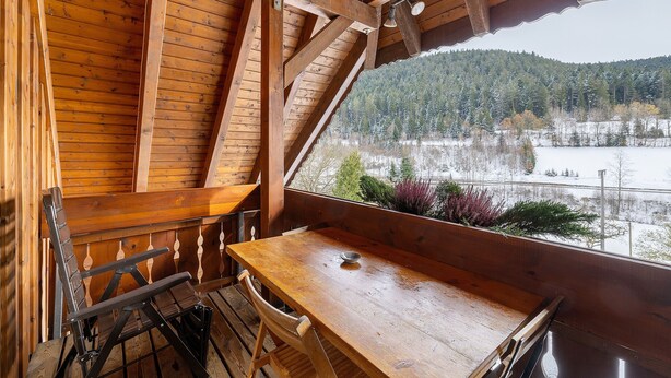 A wooden cabin with a table and chairs, a view of a snowy landscape through a window. - Apartment '8 - Flößerstuben' with Mountain View, Shared Terrace and Wi-Fi (Alpirsbach)