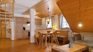 A wooden interior with a dining area, kitchen, and a staircase. - Apartment '8 - Flößerstuben' with Mountain View, Shared Terrace and Wi-Fi (Alpirsbach)