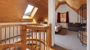 A wooden interior with a loft bedroom, a staircase, and a sofa. - Apartment '8 - Flößerstuben' with Mountain View, Shared Terrace and Wi-Fi (Alpirsbach)