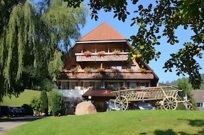 A traditional wooden building with a sloped roof, balconies with flower boxes, and a wooden cart in the foreground. - Room 'Doppelzimmer 10' with Mountain View, Shared Terrace and Wi-Fi (Alpirsbach)