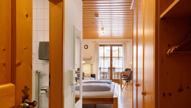 A hallway leading to a bedroom with a bed, a window, and a bathroom with a towel hanging. - Room '13' with Mountain View, Shared Terrace and Wi-Fi (Alpirsbach)
