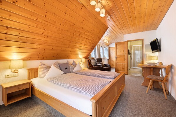 Une chambre à coucher aux murs lambrés, avec un lit, des tables de chevet, une chaise et un téléviseur.