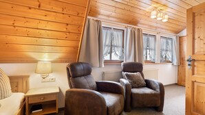 A wooden-paneled room with two leather armchairs, a small bedside table with a lamp, and a window with curtains. - Room 'Doppelzimmer 7' with Mountain View, Shared Terrace and Wi-Fi (Alpirsbach)