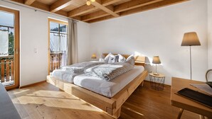 Un dormitorio con cama de madera, dos lámparas de noche, un escritorio y vistas al exterior.