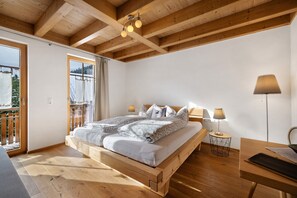 Un dormitorio con cama de madera, dos lámparas de noche, un escritorio y vistas al exterior.