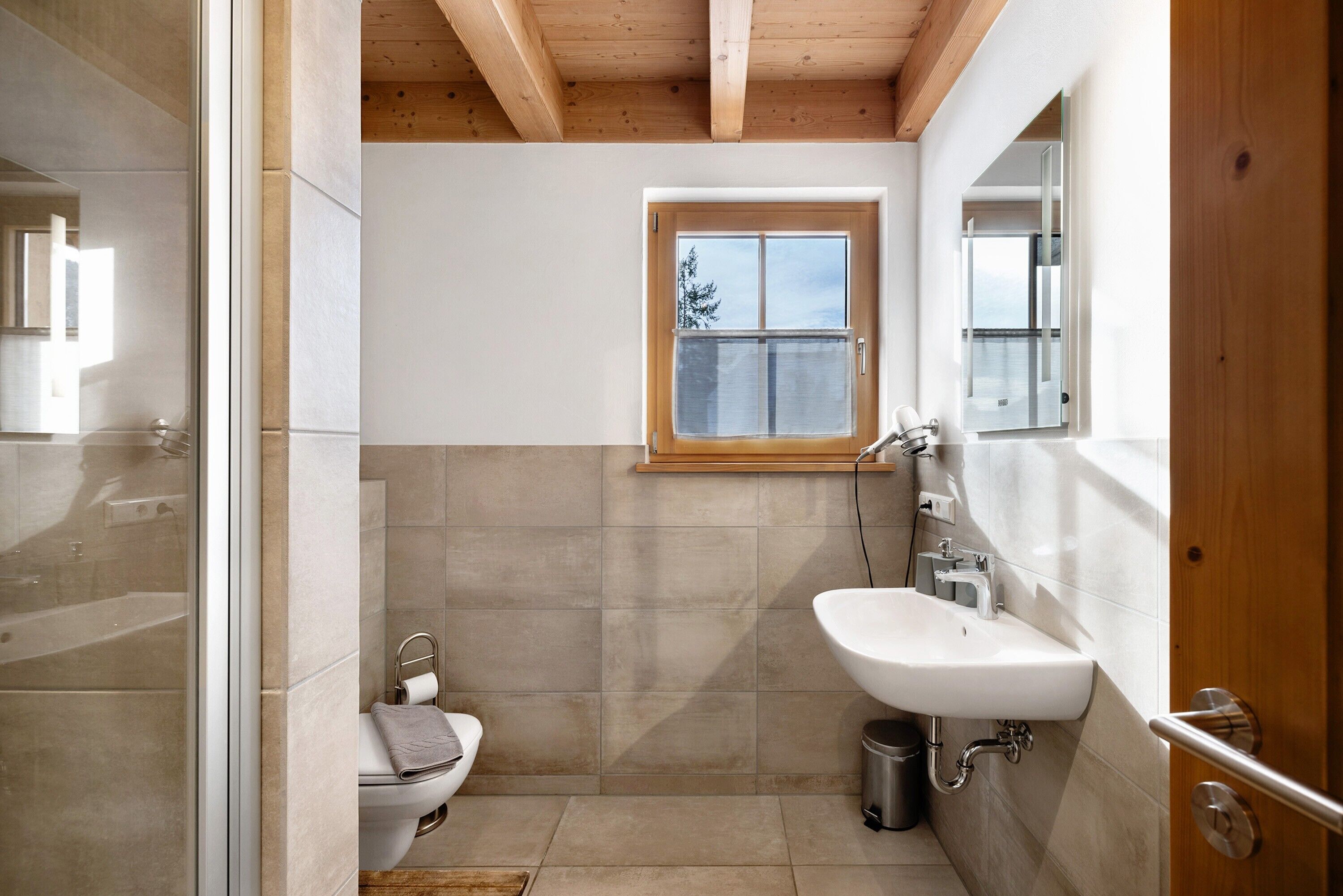 Ein modernes Badezimmer mit Toilette, Waschbecken und Fenster.