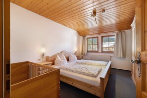 Ein Schlafzimmer mit Holzboden, einem Bett, Nachttischen, einem Fenster und einem Heizkörper.