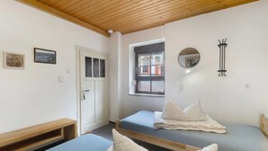 Une chambre avec deux lits, un plafond en bois, une fenêtre donnant sur un paysage agréable et une porte.