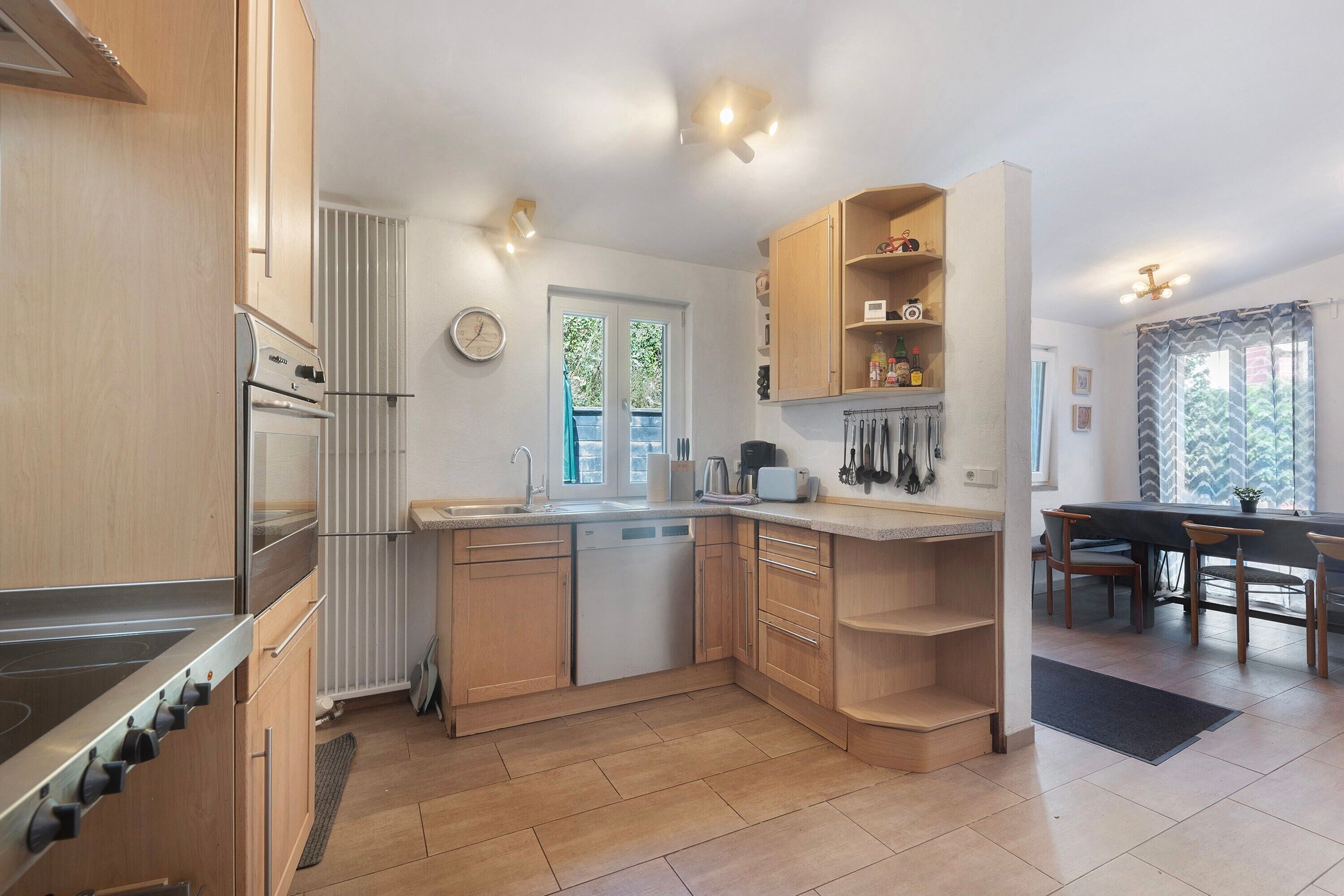 Eine moderne Küche mit Holzausstattung, einem eingebauten Backofen und einem Essbereich mit Tisch und Stühlen.