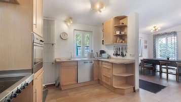 Eine moderne Küche mit Holzausstattung, einem eingebauten Backofen und einem Essbereich mit Tisch und Stühlen.
