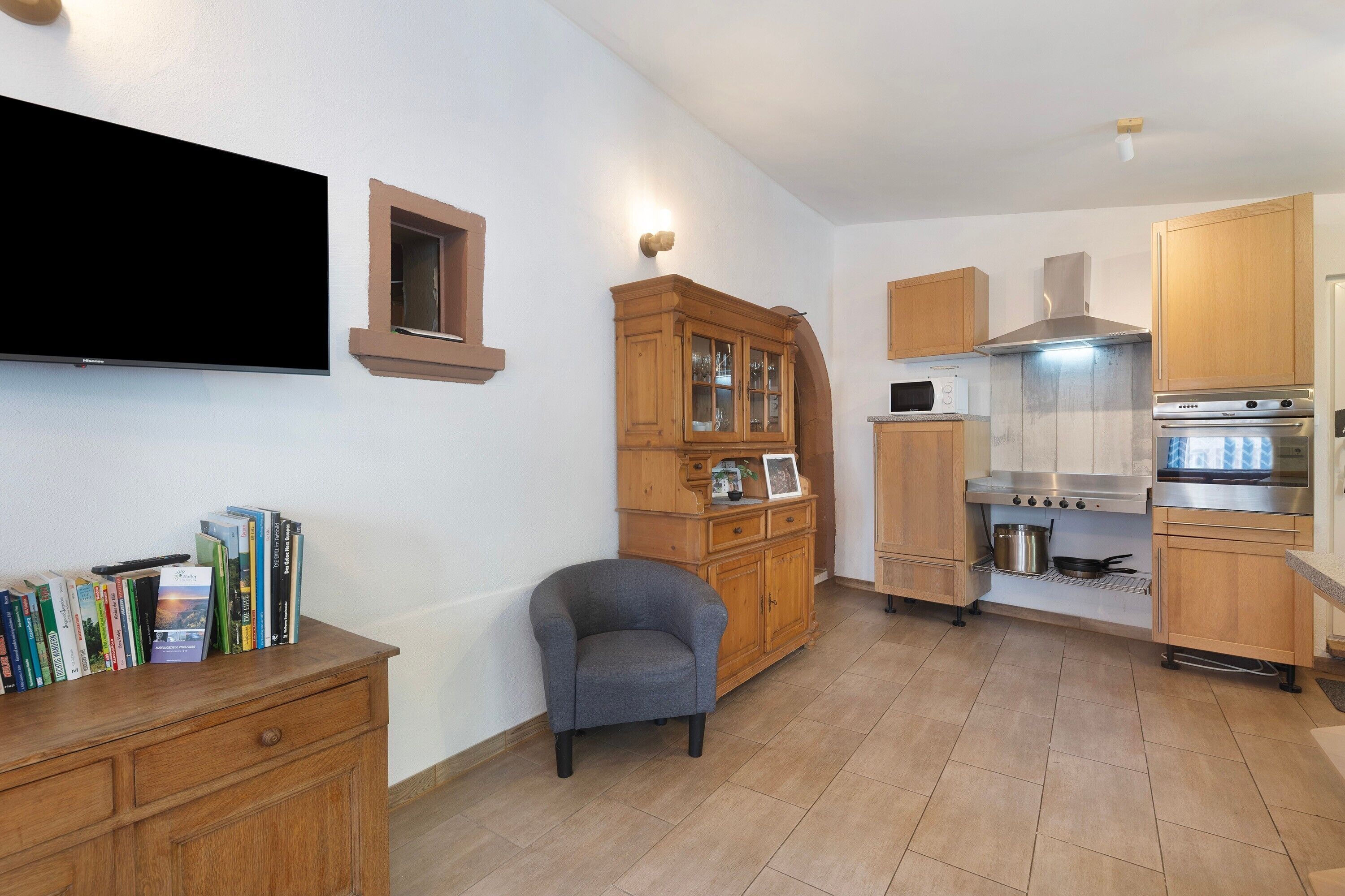 Una cucina con mobili in legno, forno a incasso e microonde.