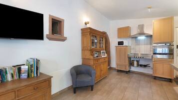 Una cucina con mobili in legno, forno a incasso e microonde.