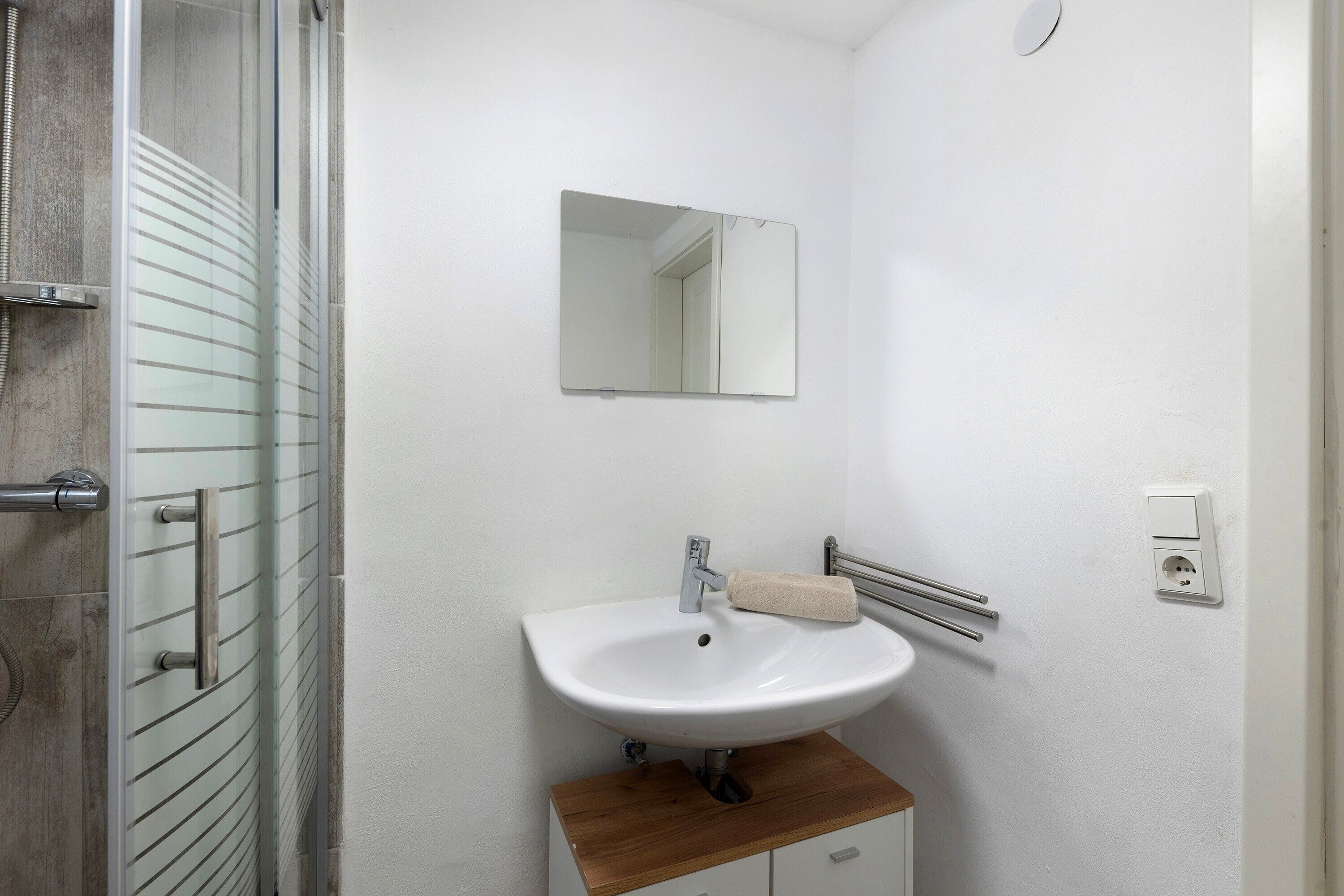 Ein Badezimmer mit Dusche, Waschbecken, Spiegel und Handtuchhalter.