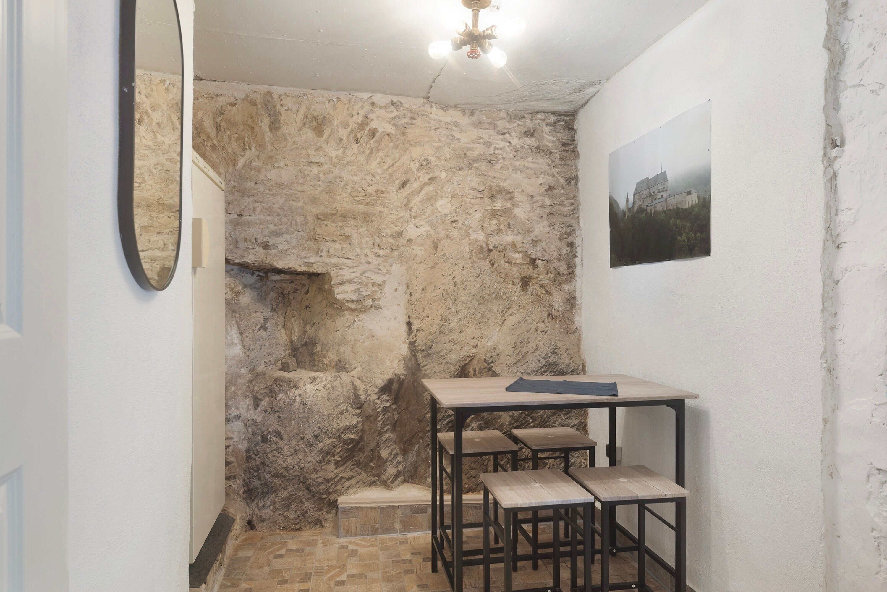 A room with a stone wall, a wooden table, and two benches.