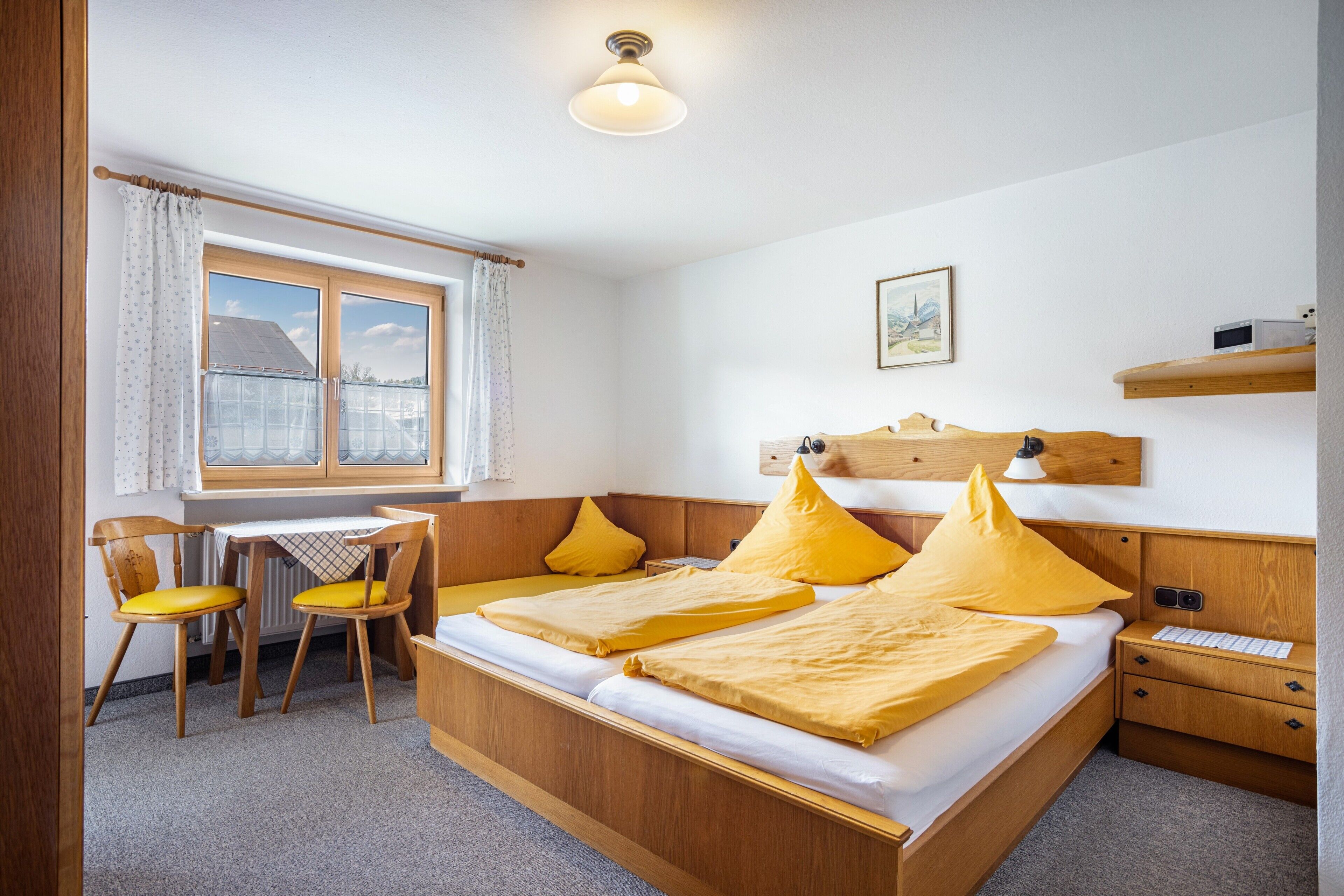 Ein Zimmer mit einem Bett, zwei Stühlen, einem Schreibtisch und einem Fenster.