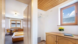 A bedroom with a bed, a desk, a chair, a wardrobe, and a window with a view. - Holiday Apartment Rubihorn with Mountain View, Balcony and Wi-Fi (Oberstdorf)