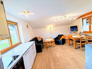 A compact living space with a kitchenette, a sofa, a dining table, and a TV.