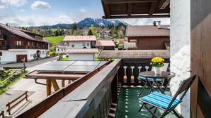 A balcony with a table, chairs, and a potted plant. - Apartment Nebelhorn with Mountain View, Balcony and Wi-Fi (Oberstdorf)