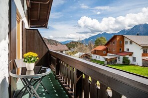 A balcony with a wooden railing, a glass table, and a potted plant.