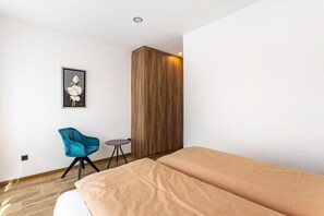 A bedroom with a bed, a wardrobe, a chair, and a small table. - Apartment 'Sophie Stecker' with Mountain View, Private Terrace and Wi-Fi (Schmallenberg)