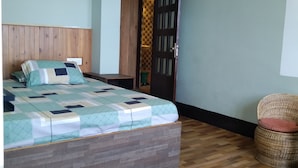 A bedroom with a wooden bed, a checkered door, and a woven chair. - Broadview Homestay  (Darjeeling)
