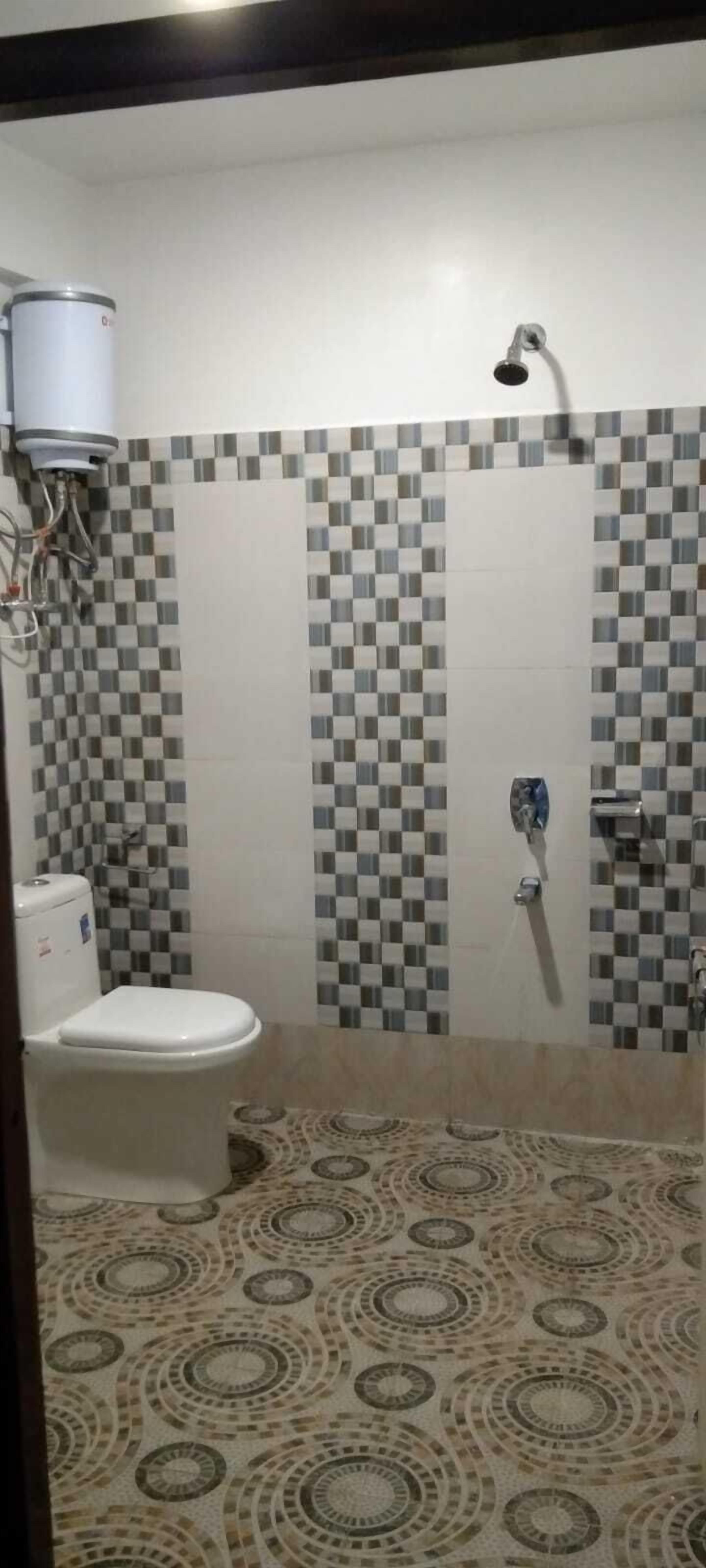 A bathroom with a toilet, a shower, and a tiled wall.