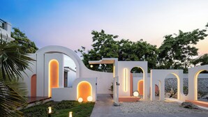 Une structure architecturale moderne, dotée d’arcades illuminées et d’un chemin menant à l’entrée d’un bâtiment.