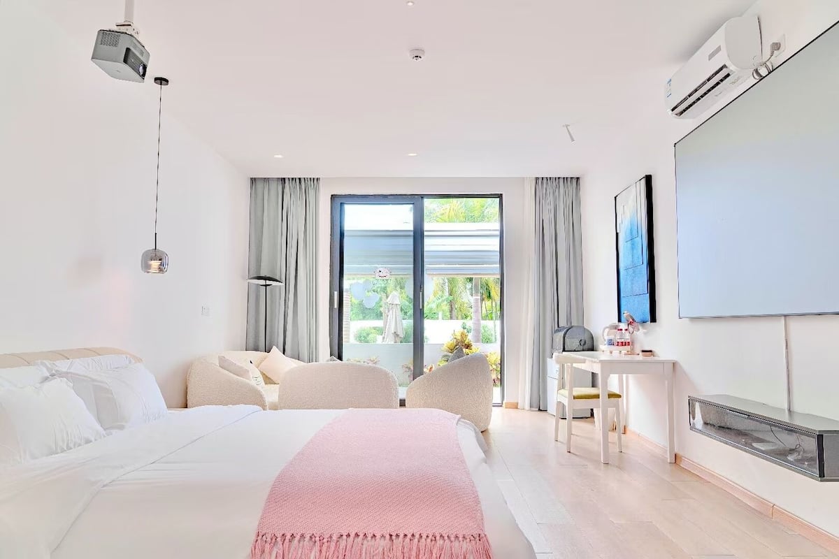A modern bedroom with a large bed, a desk, and a TV.