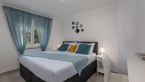 A modern bedroom with a bed, bedside table, and a chair. - Family-Friendly Apartment Near the Coast (Crikvenica)