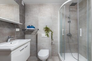 A modern bathroom with a glass-enclosed shower, a white sink, and a toilet. - Beautiful home with swimming pool and balcony (Crikvenica)
