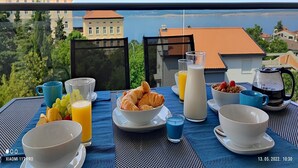 A breakfast setup with croissants, fruit, and beverages on a table with a scenic view.